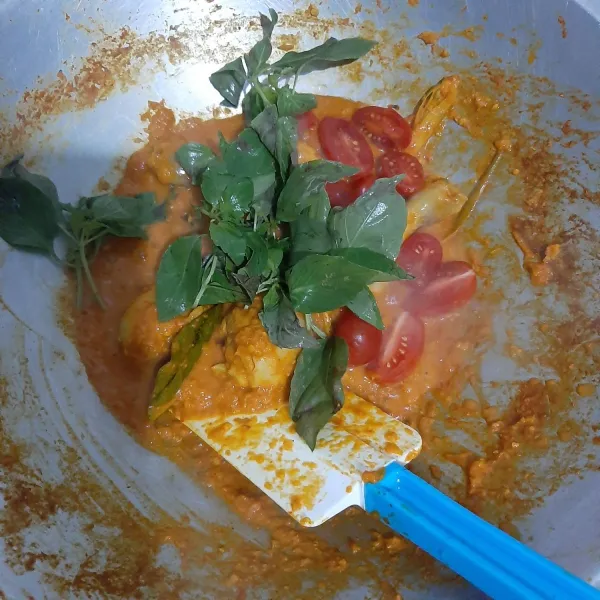 Setelah ayam matang, masukkan daun kemangi dan tomat yang sudah dibersihkan dan dipotong. Masak sebentar dan ayam woku siap dinikmati.