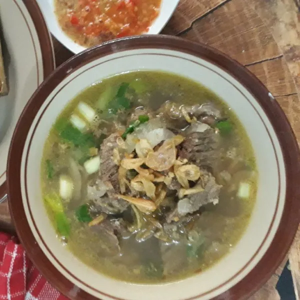 Sajikan coto makasar dengan ketupat dan sambal.