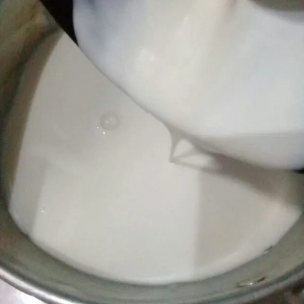 Lalu tuang susu hangat ke mangkuk yang ada yogurt plain kira-kira 5 sdm, aduk rata, lalu tuang kembali semuanya ke panci yang ada susu hangat.