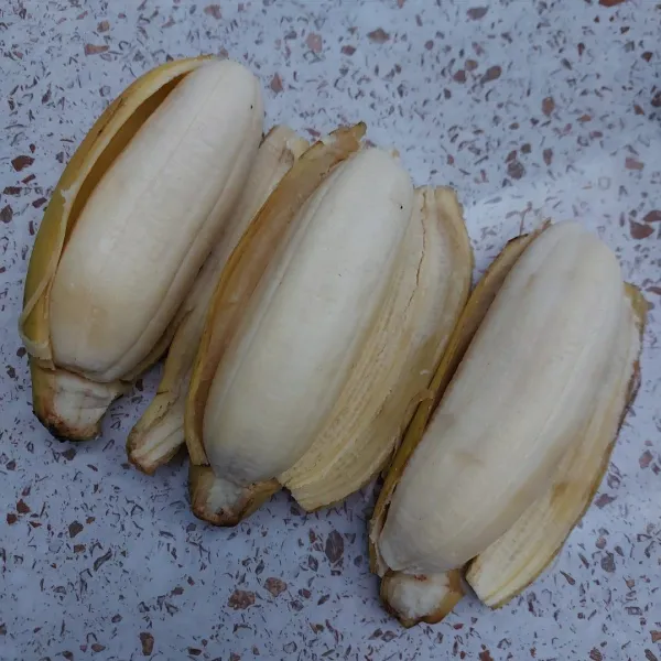 Kupas pisang. Gosok-gosok perlahan permukaan pisang dengan kulitnya sampai licin.
