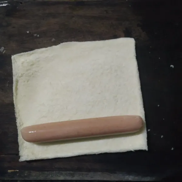 giling roti tawar sampai tipis, lalu beri sosis di atasnya.