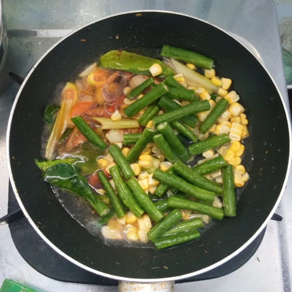 Masukkan jagung dan kacang panjang. Tambahkan air. Aduk rata. Masak sampai empuk.