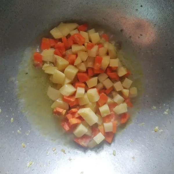 Haluskan bawang merah dan bawang putih. Tumis hingga harum. Masukkan kentang, wortel dan sedikit air.