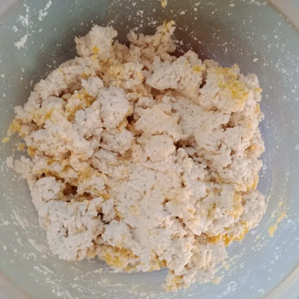 Letakkan dalam wadah, tambahkan garam halus, kaldu jamur bubuk, baking powder, dan kuning telur. Aduk-aduk atau remas-remas sampai rata.
