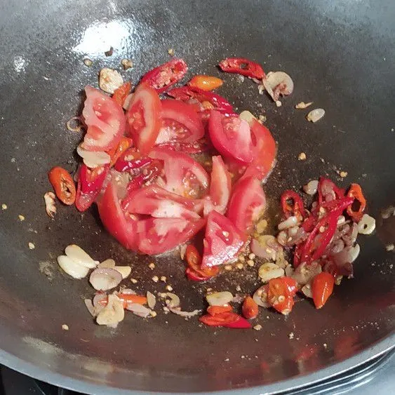 Masukkan irisan tomat, tumis hingga tomat layu.