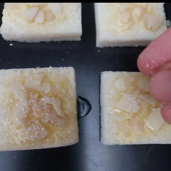 Beri topping kenari cincang dan gula pasir. Tekan-tekan sedikit agar kenari menempel di roti.
