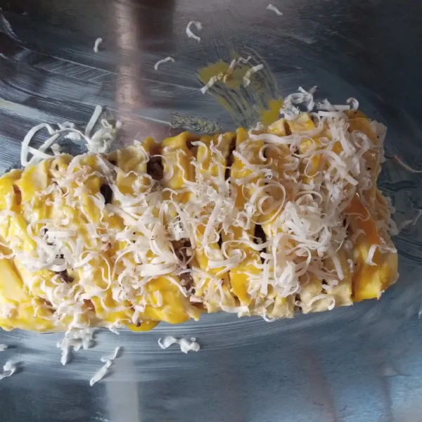Olesi bagian atas menggunakan kuning telur, lalu beri topping taburan keju