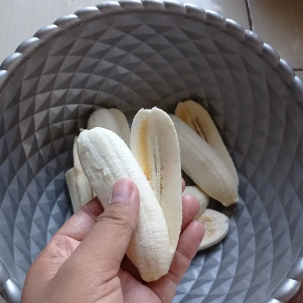 Kupas pisang lalu belah tapi jangan sampai putus.