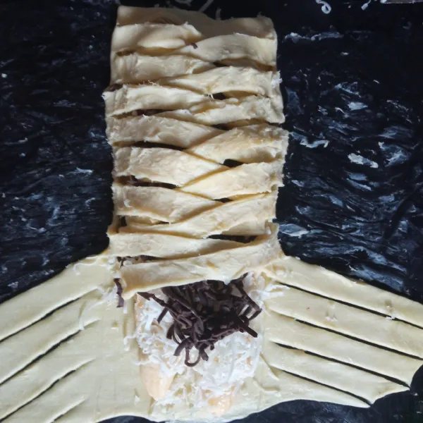 Tutupi isian dengan puff pastry yang sudah dipotong tadi dengan posisi menyilang bergantian seperti dikepang