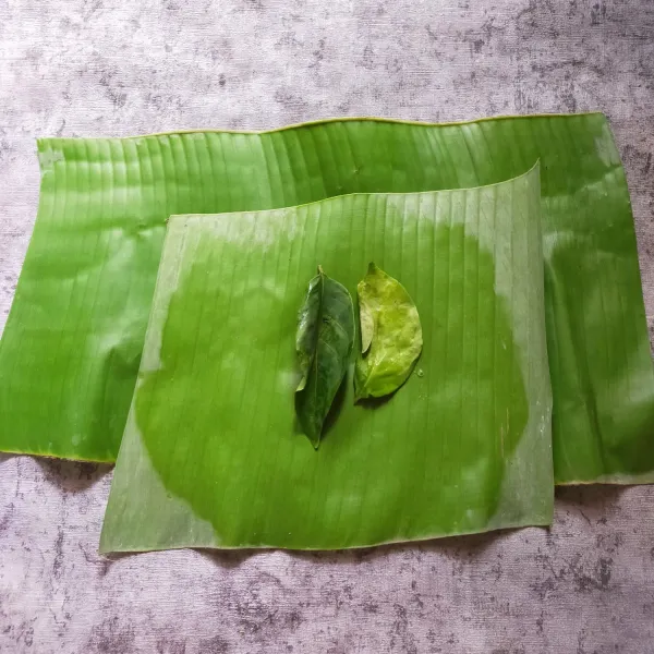 Letakan daun salam di atas dua lembar daun pisang.