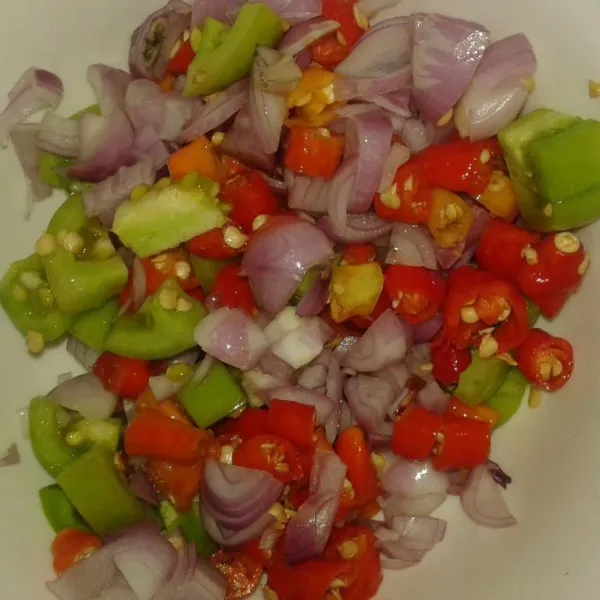 Dalam wadah mangkuk, campur potongan cabe rawit merah, bawang merah dan bawang merah jadi satu.