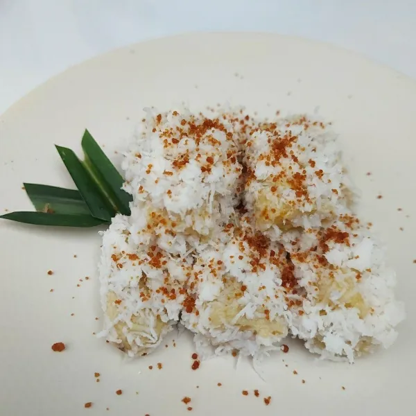 Taruh pisang balut kelapa dalam piring lalu beri topping gula aren bubuk. Sajikan.