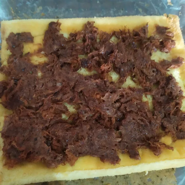 Selagi panas, keluarkan kue di atas lap bersih / kertas, buka kertas yang menempel, tutup rapat kue dengan loyangnya, diamkan sampai dingin. Beri isian ratakan di seluruh permukaan kue.