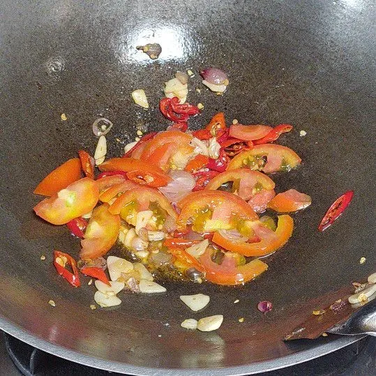 Tumis bawang merah, bawang putih dan cabai dengan secukupnya minyak goreng hingga harum. Masukkan irisan tomat. Tumis kembali hingga tomat layu.