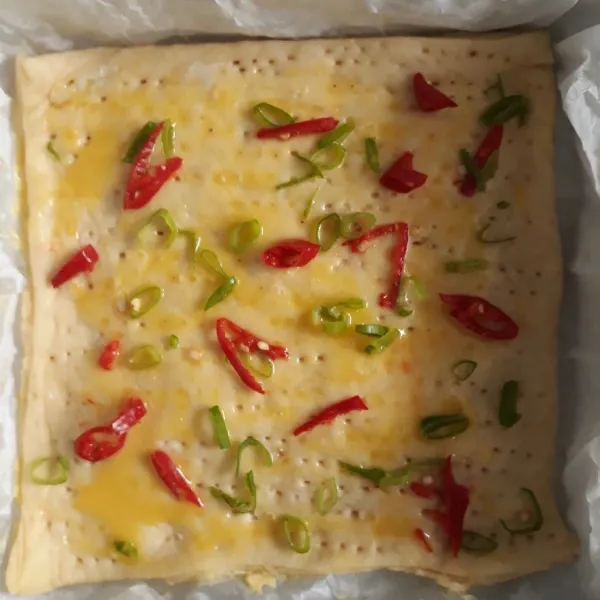 Tusuk adonan dengan garpu. Olesi dengan kuning telur. Taburi irisan daun bawang dan cabe merah. Panggang sampai matang.
