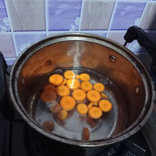 Didihkan air di panci, kemudian masukkan wortel. Masak sampai wortel setengah matang.