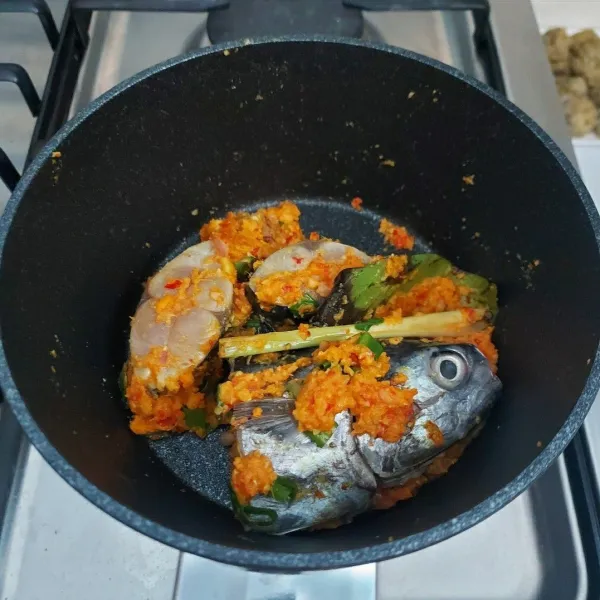 Tumis bumbu halus bersama serai, lengkuas dan daun salam sampai harum. Masukkan ikan dan daun bawang, aduk rata.