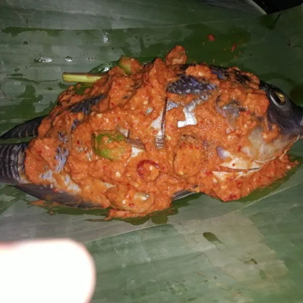 Siapkan daun pisnag. Lalu letakan daun salam di atasnya. Lumuri ikan dengan bumbu halus dan sertakan serai dan belimbing wuluh. Gulung ikan dengan daun lalu sematkan kedua sisi dengan lidi.