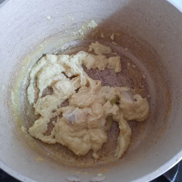 Membuat Ikan Kuah Kuning: panaskan minyak. Tumis bumbu halus, serai dan lengkuas hingga matang.