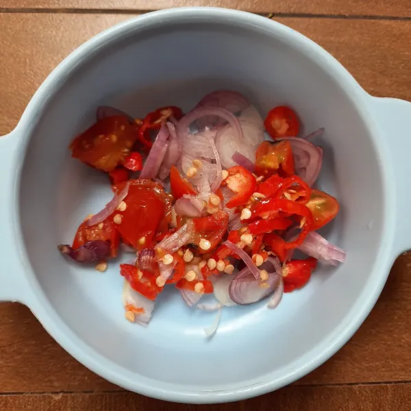 Membuat sambal colo-colo: masukkan tomat, irisan cabai dan bawang merah dalam wadah.