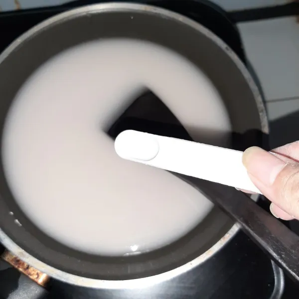 Campurkan tepung sagu, air, dan garam. Aduk rata dulu hingga tidak ada gerindil. Baru nyalakan kompor dengan api kecil. Aduk terus hingga jadi adonan kenyal dan bening. Ini namanya papeda. Sisihkan.