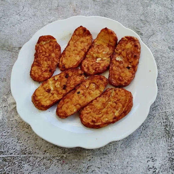 Angkat. Masukkan piring, tekan-tekan sampai tempe menjadi penyet.