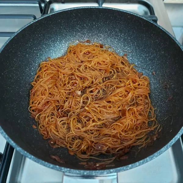 Masukkan bihun, aduk-aduk sampai warna coklatnya merata dan sampai airnya sat (berkurang/kering). Angkat.