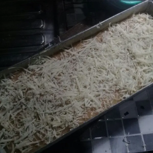 Tuang ke dalam loyang yang sudah dioles margarin dan tepunng terigu. Beri topping keju parut.