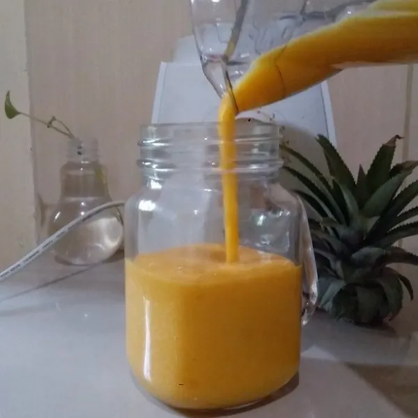 Tuang pineapple mango smoothies ke dalam gelas saji.