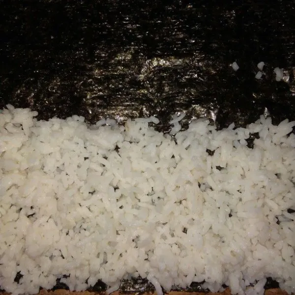 Ambil nasi yang sudah dicampur garam dan air jeruk nipis. Tata di atas nori.