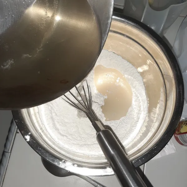 Masukkan larutan gula ke adonan tepung. Aduk rata hingga tidak ada gerindil. Saring jika perlu.