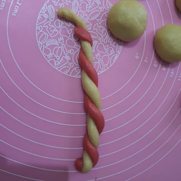 Ambil satu adonan merah dan putih. Buat memanjang dan jalin adonan, lalu ambil salah satu ujung gulung ke dalam lalu bentuk seperti bunga.