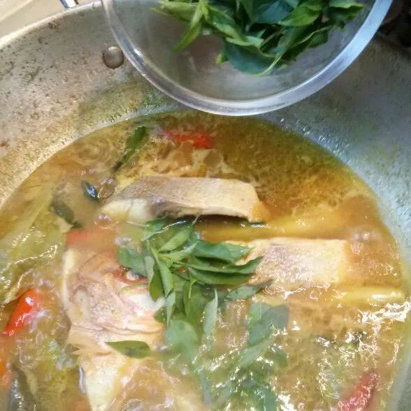Masukkan ikan. Masak sampai ikan setengah matang. Lalu tambahkan daun kemangi.