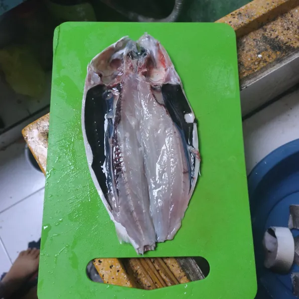 Bersihkan sisik ikan. Belah dua dan buang isi perutnya. Cuci kembali dan sisihkan.