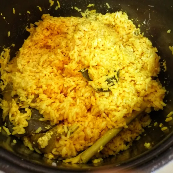 Setelah bumbu 30 menit, aduk nasinya lalu tutup lagi sampai matang.