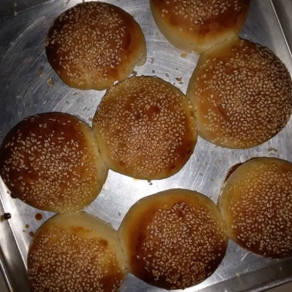 Panaskan oven dengan api besar. Letakan mangkok stenlis berisi air di rak bawah oven tangkring. Setelah mendidih, masukan adonan burger. Panggang selama 10 menit di rak tengah. Kemudian pindahkan rak atas selama 10 menit. Setelah berwarna kecoklatan, keluarkan dari oven. Langsung oleskan butter