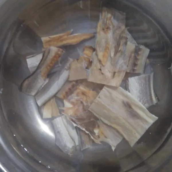Cuci bersih ikan asin dengan air mengalir.
