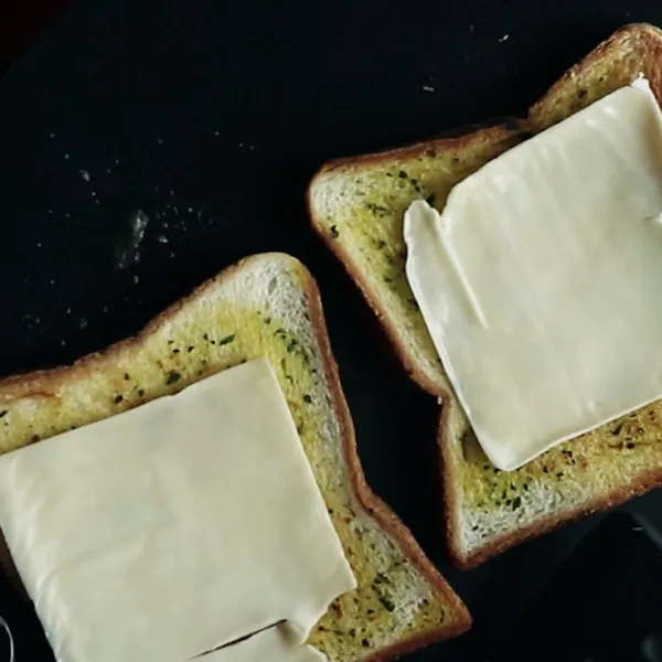 Tambahkan keju slice di atas roti dan masak hingga roti matang.