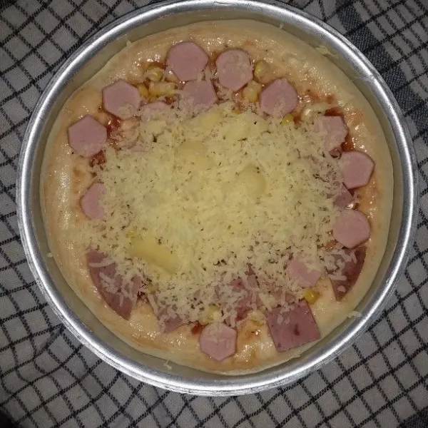 Setelah mengembang. Oleskan permukaan adonan dengan saus tomat, saus sambal dan saus barbeque. Takaran sesuaikan dengan selera. Taburkan jagung manis pipil, irisan sosis, irisan smoked beef dan parutan keju mozarella.
