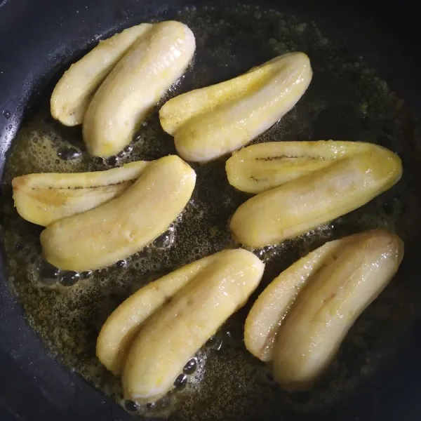 Kupas pisang lalu belah tapi tidak sampai putus lihat contoh gambar. Panaskan 2 sdm margarin ke dalam teflon lalu goreng pisang sampai berubah wanah kecoklatan.