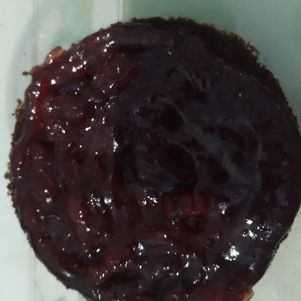 Bagian bawah brownies diberi selai strawberry.