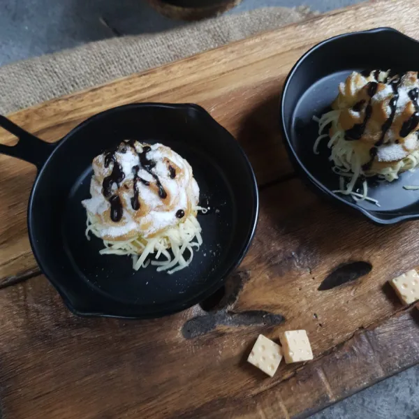 Tambahkan parutan keju. Sajikan denga taburan gula bubuk dan coklat cair.