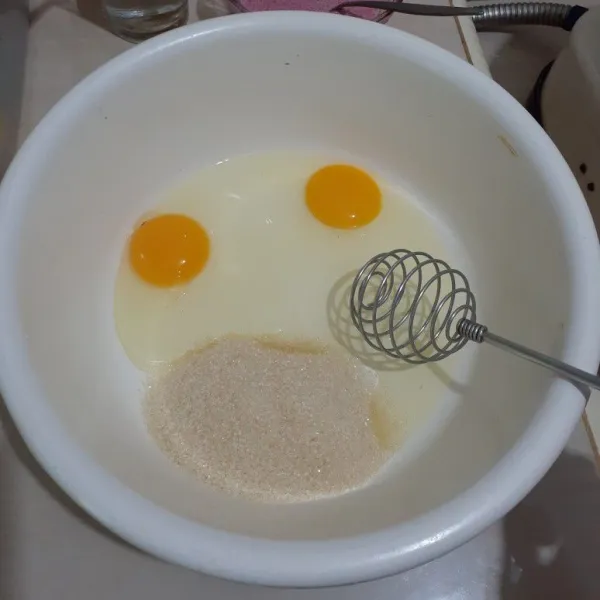 Lalu siapkan wadah lain untuk telur dan gula. Kocok hingga berjejak dan berwarna putih.