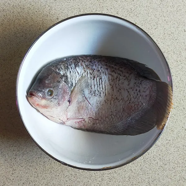 Cuci bersih ikan, kerat badan kedua sisinya, kucuri air jeruk nipis dan balur garam. Diamkan minimal 30 menit