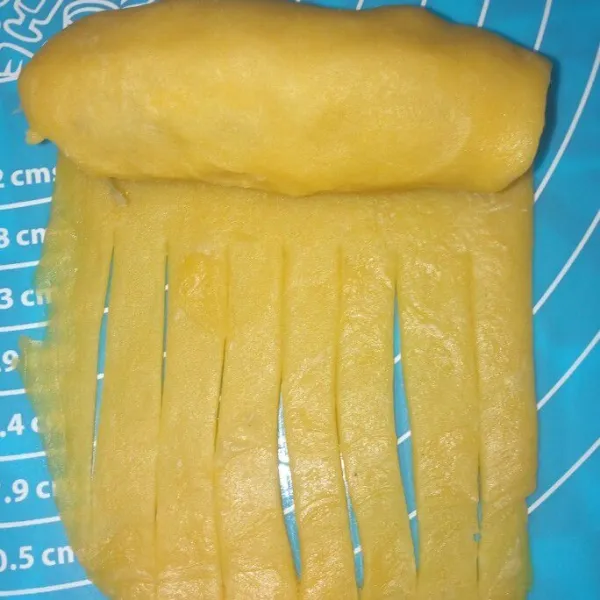 Ambil 1 bagian pipihkan letakan pisang di atasnya belah jangan sampai putus selipkan keju atau mesis lalu tutup dengan sedikit adonan sisanya buat irisan memanjang lalu gulung