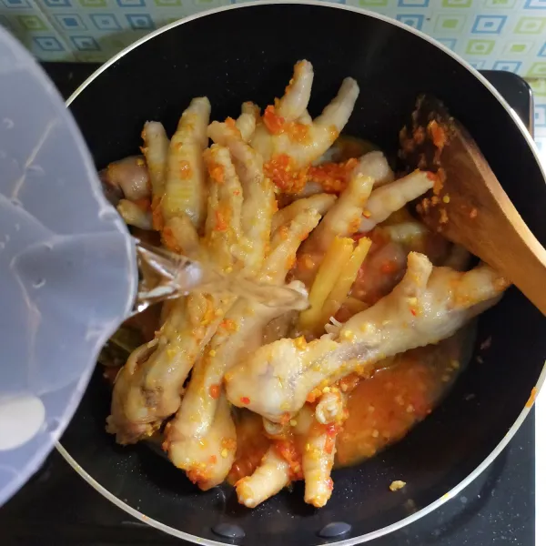 Masukkan ceker yang sudah direbus tadi ke dalam wajan, lalu tambahkan air.