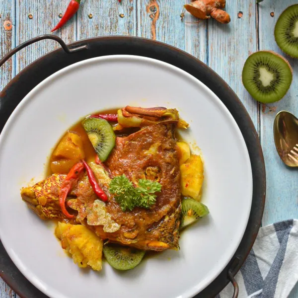 Masukkan potongan buah kiwi, Mmatikan api dan sajikan Lempah Kuning Kepala Ikan Kakap Merah dengan nasi putih hangat.