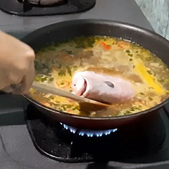 Setelah mendidih masukan kepala kakap. Masak sisi pertama 12 menit, lalu balik sisi satunya 10 menit.
