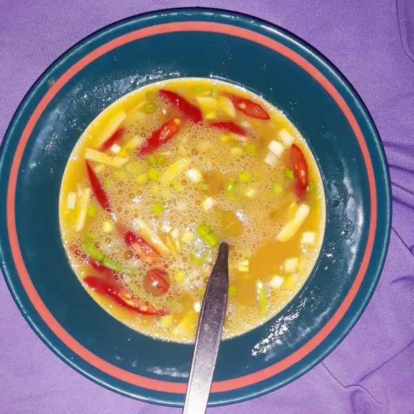 Masukan telur ke mangkuk, masukan garam dan bumbu-bumbu yang sudah dipotong-potong