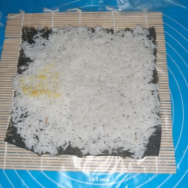 Siapkan nori yang besar, lalu diatasnya beri nasi sampai rata seluruh permukaan. Untuk resep nasi uduk, bisa dilihat di halaman saya.